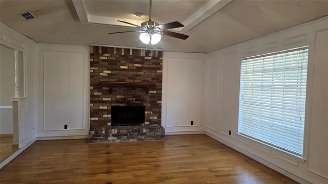 a view of a livingroom with a fireplace a ceiling fan and window