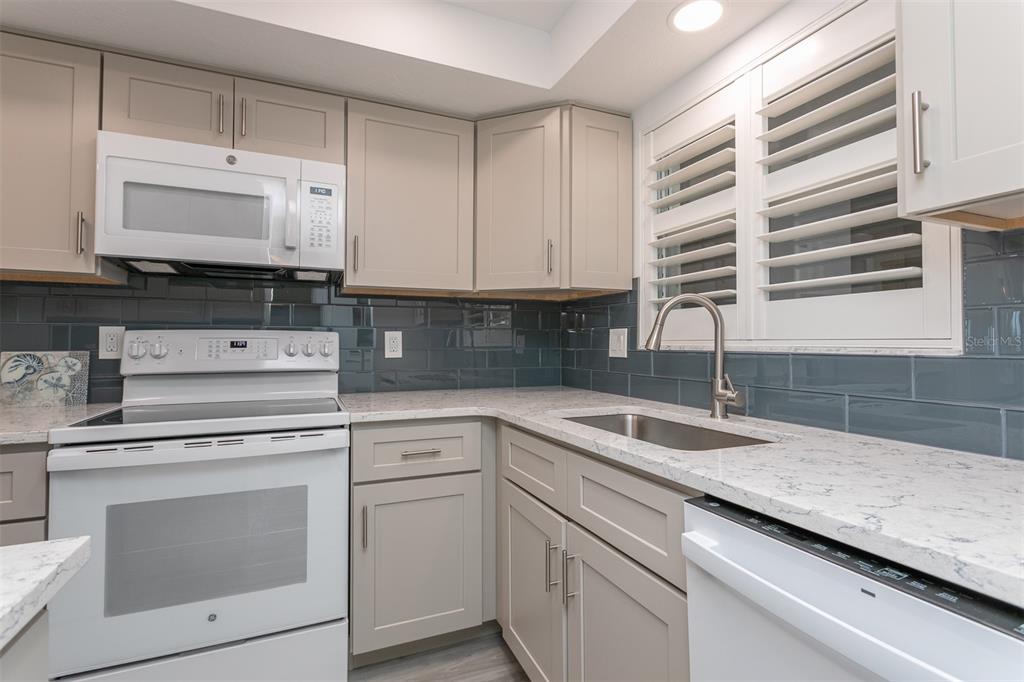 633 Alhambra Road, Unit 305 Venice, FL 34285 - Photo 16 of 43 a kitchen with granite countertop white cabinets and white appliances