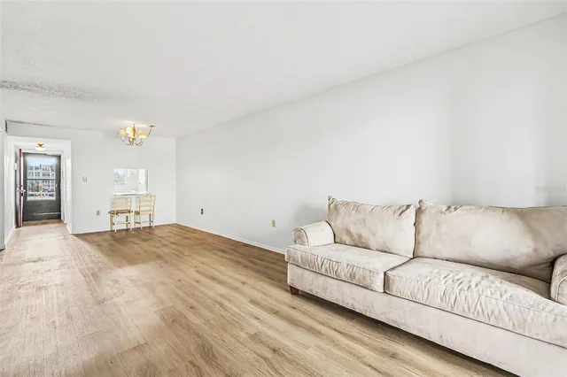a living room with a couches and kitchen view with wooden floor