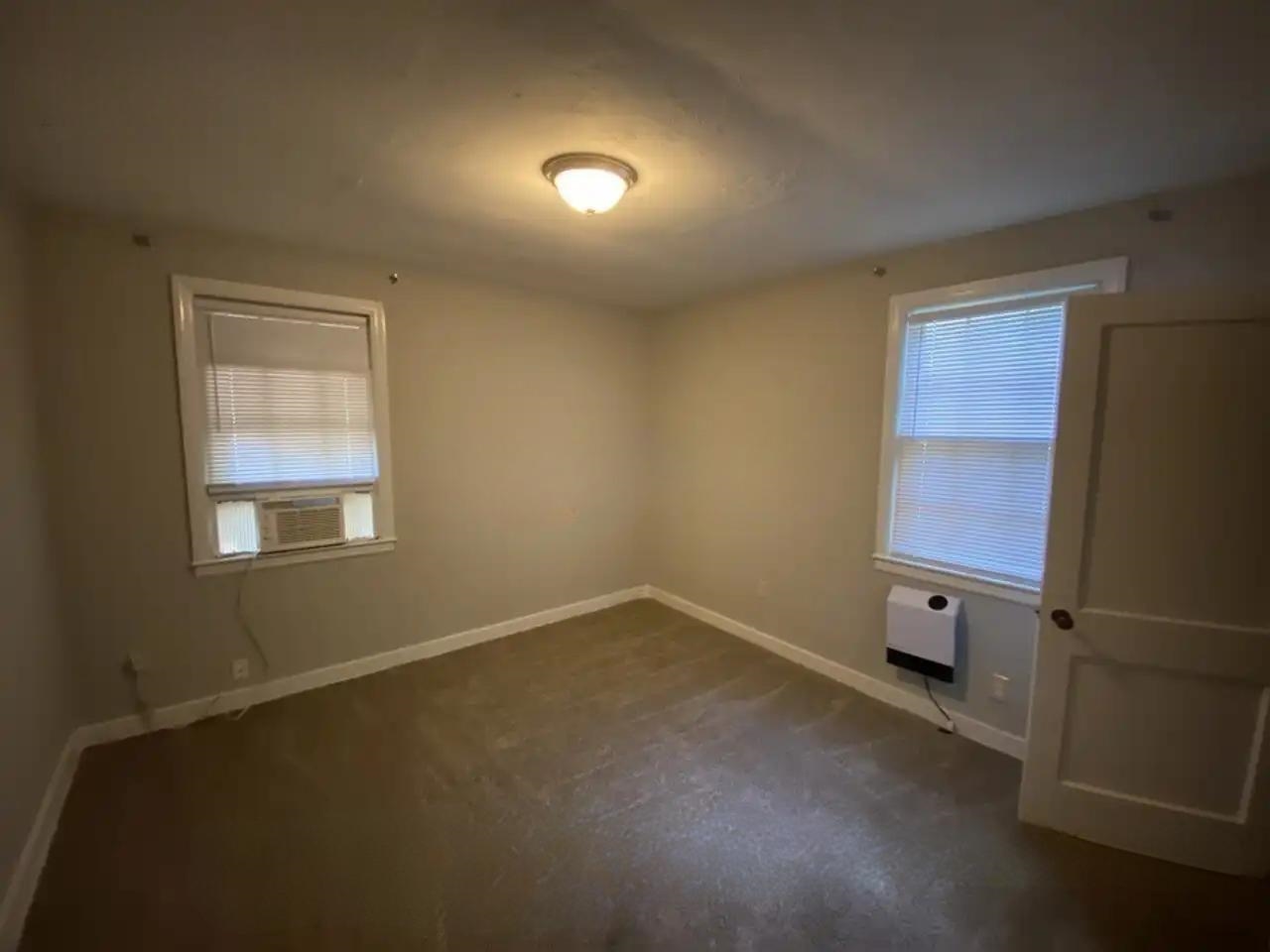 494 East Raines Road Memphis, TN 38109 - Photo 5 of 9 Spare room featuring cooling unit, dark colored carpet, and heating unit