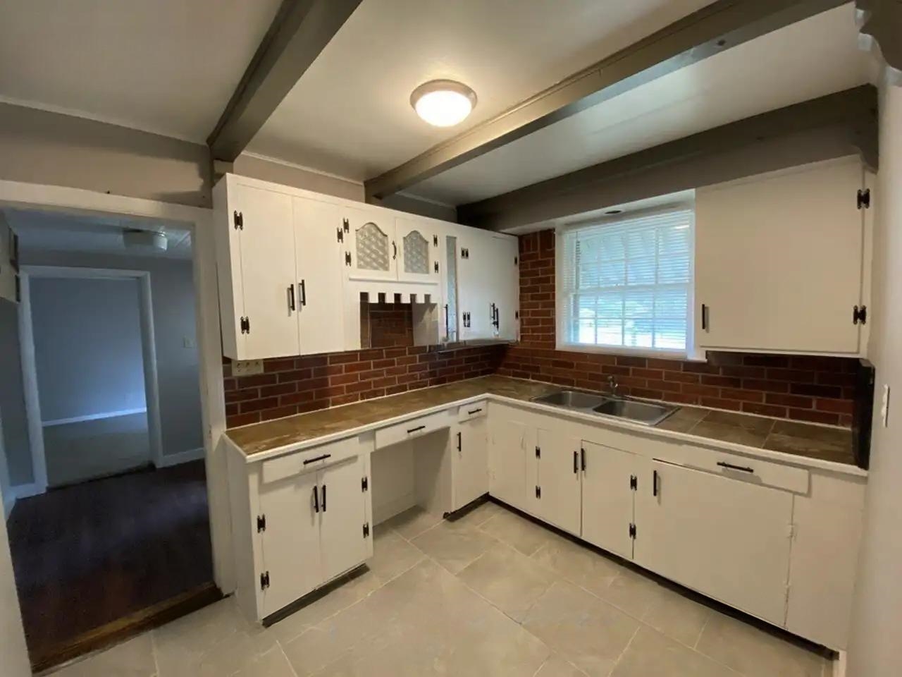 494 East Raines Road Memphis, TN 38109 - Photo 8 of 9 Kitchen with backsplash, beam ceiling, white cabinets, and light tile patterned flooring