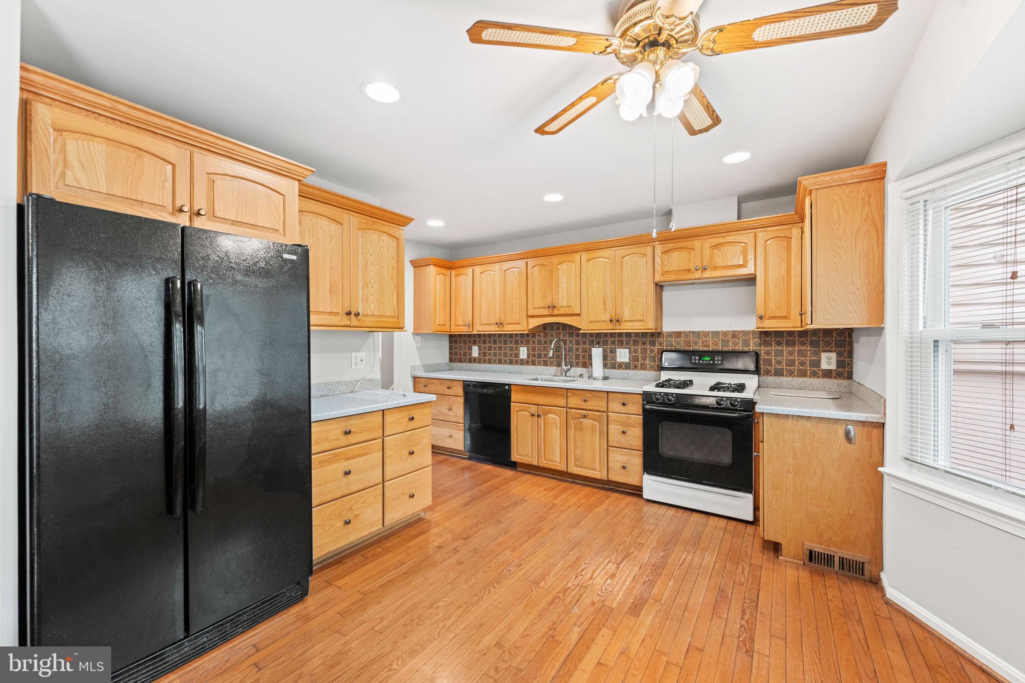 8000 Lady Lewis Court Springfield, VA 22153 - Photo 11 of 44 a kitchen with stainless steel appliances granite countertop a refrigerator a sink dishwasher a stove and white countertops with wooden floor