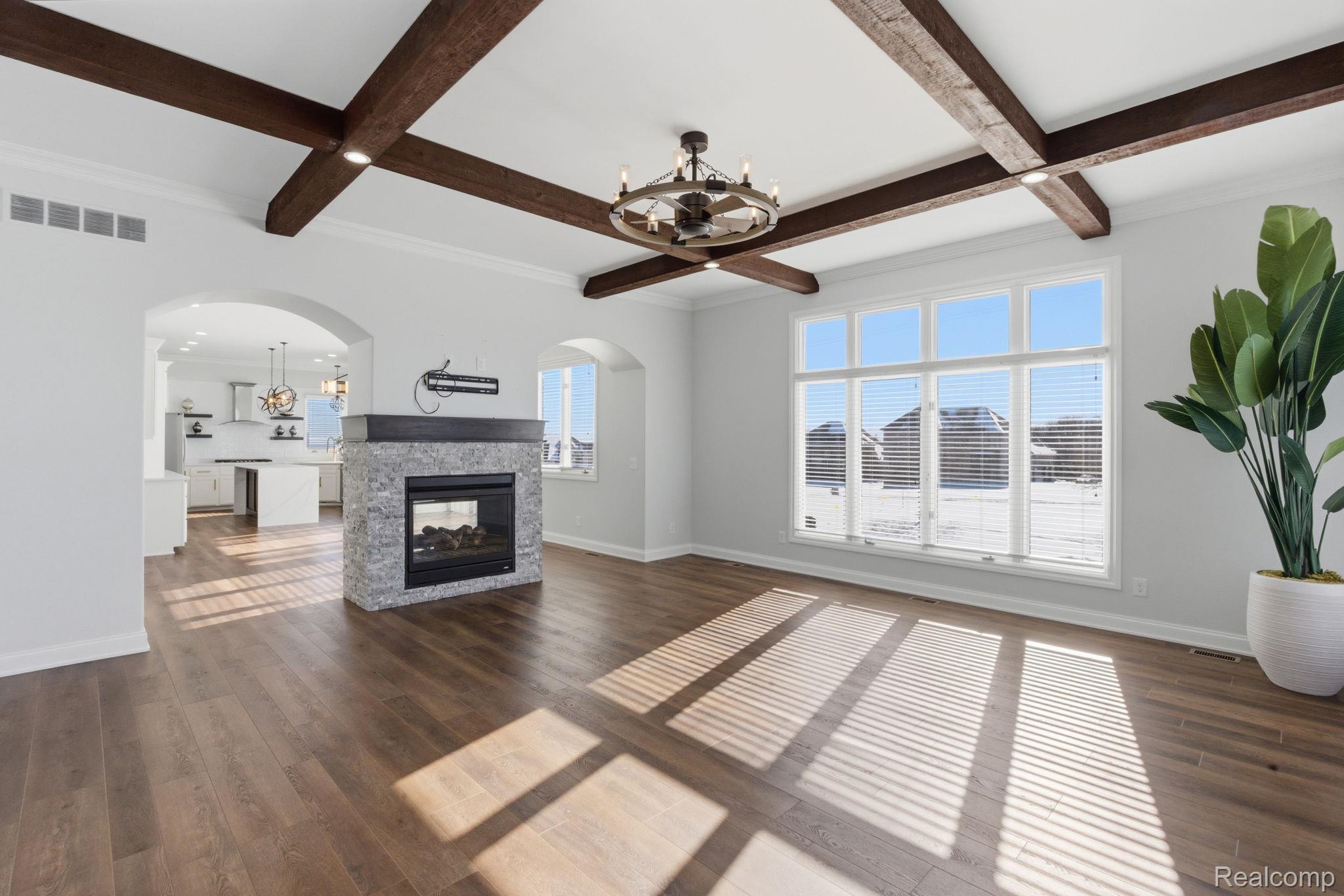 8844 Ridge Drive Washington, MI 48095 - Photo 2 of 51 Unfurnished living room with a chandelier, a multi sided fireplace, coffered ceiling, arched walkways, and dark wood finished floors