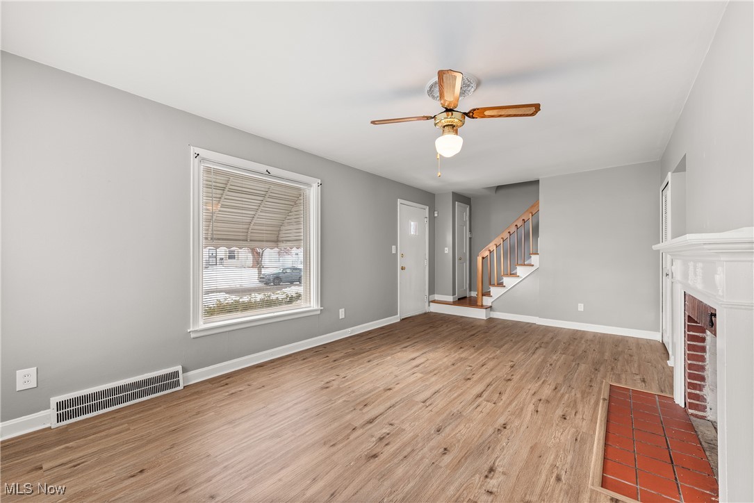 4041 Wilmington Road Cleveland, OH 44121 - Photo 3 of 38 Unfurnished living room with light wood-type flooring, a fireplace, ceiling fan, and stairway