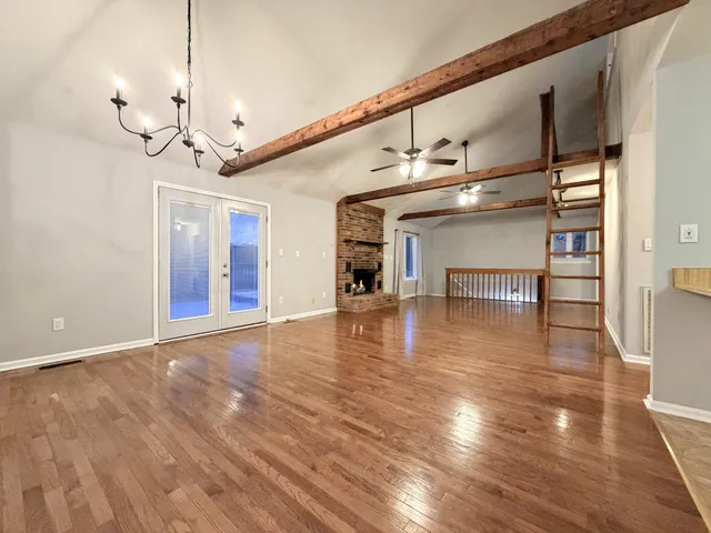 a view of a room with wooden floor fire place and windows