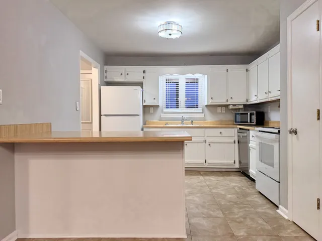 a kitchen with white cabinets and white appliances