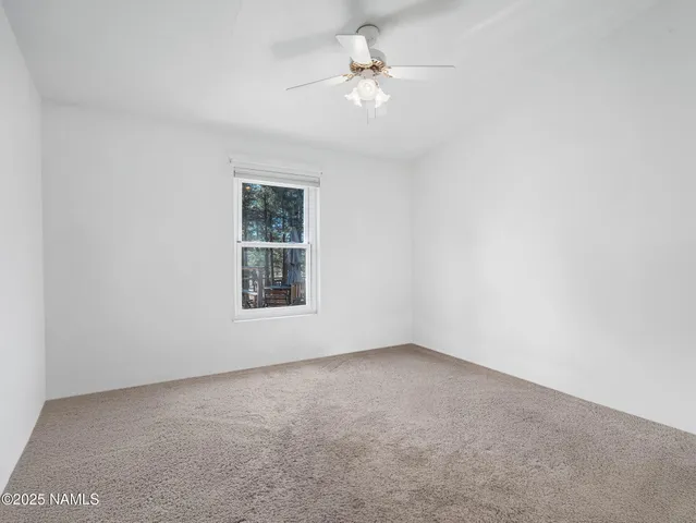 an empty room with a window and a ceiling fan
