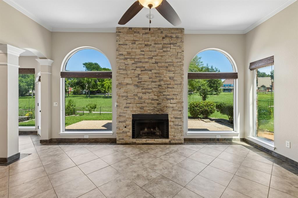 2925 Sunset Ridge McKinney, TX 75072 - Photo 9 of 33 Another view of the bright and inviting family room centered around an impressive stone fireplace, with oversized arched windows that flood the room with natural light and frame the scenic outdoor setting.