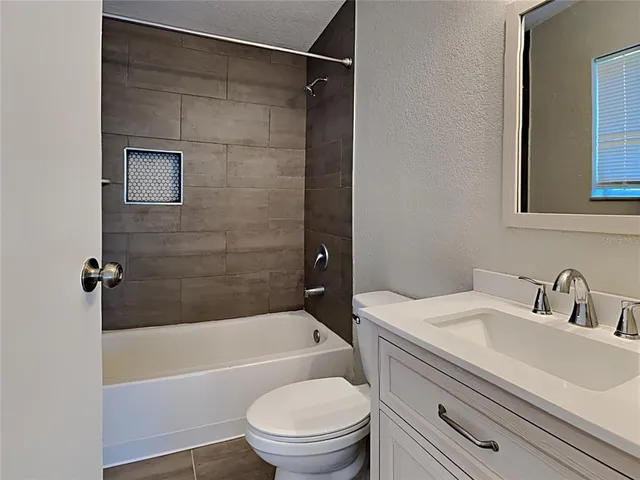 a bathroom with a granite countertop bathtub shower sink vanity and toilet