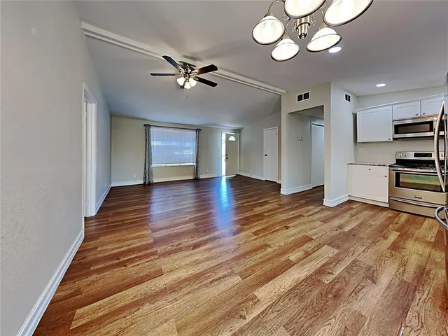 a view of an empty room with a window and wooden floor