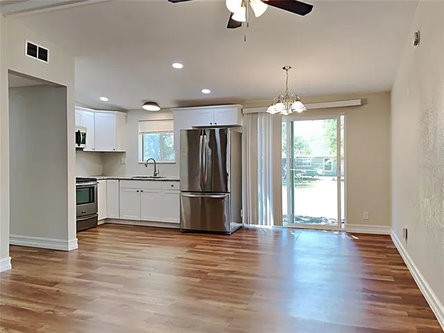 a kitchen with stainless steel appliances wooden floor and chandelier