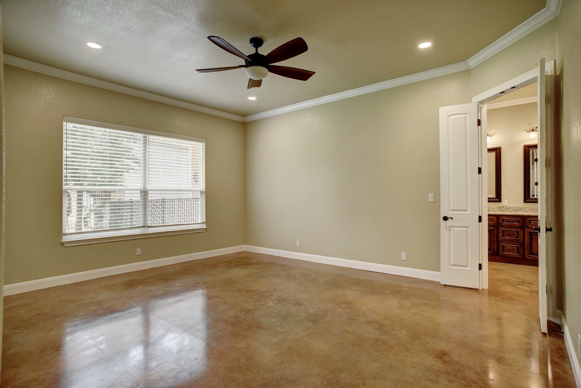 115 Pine Point Cove Elgin, TX 78621 - Photo 14 of 39 A spacious bedroom features sleek concrete flooring and a modern ceiling fan, creating a cool and open atmosphere.