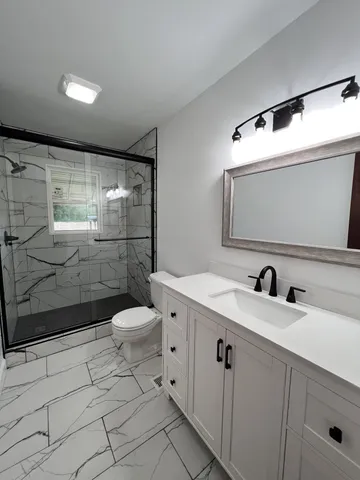 a bathroom with a sink a toilet and shower