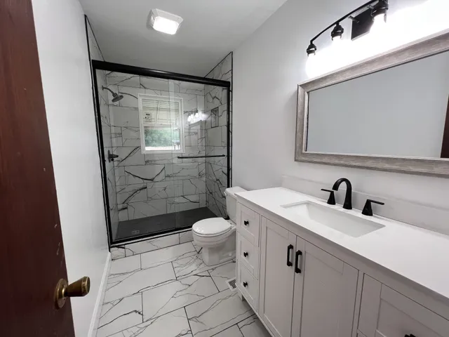 a bathroom with a granite countertop sink toilet and shower
