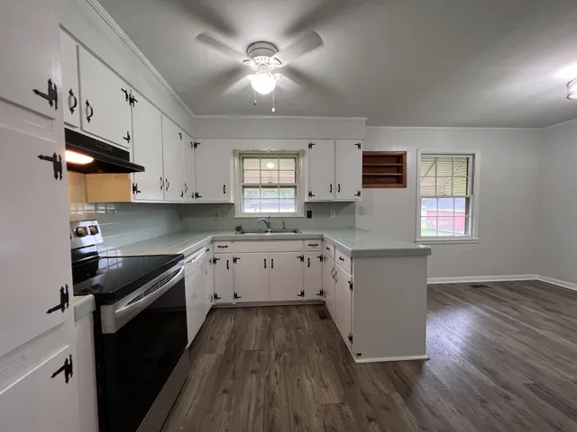 a kitchen with granite countertop a stove a sink a refrigerator and cabinets