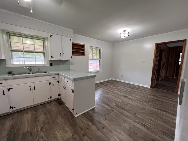 a kitchen with cabinets wooden floor and a window