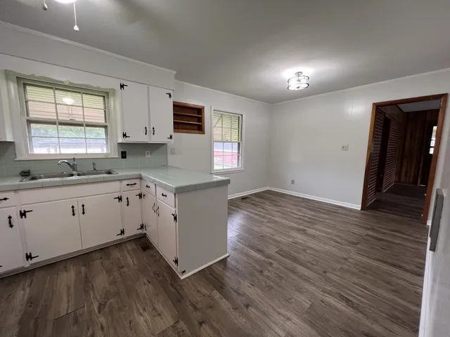 a kitchen with cabinets wooden floor and a window
