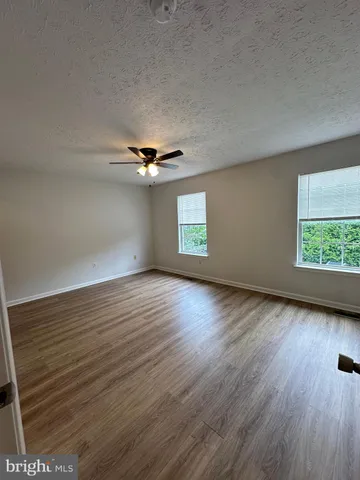 an empty room with wooden floor chandelier and windows