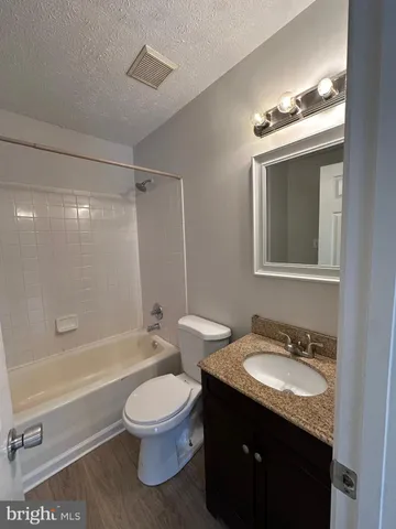 a bathroom with a granite countertop sink toilet a mirror and bathtub