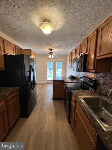 a kitchen with stainless steel appliances a stove a refrigerator a sink a stove white cabinets and wooden floor