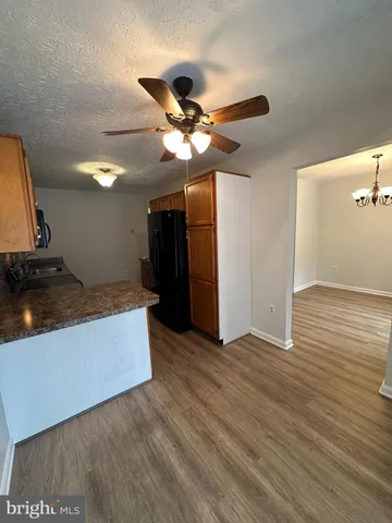a view of a kitchen with wooden floor and a ceiling fan
