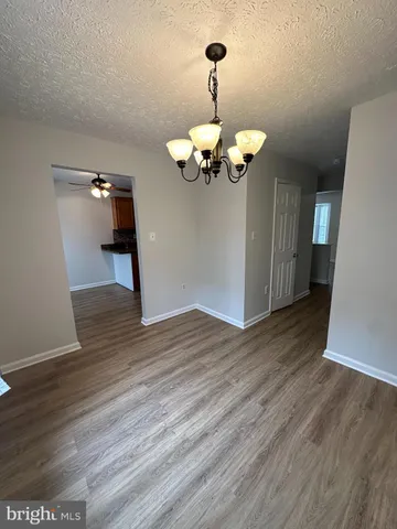a view of a room with wooden floor chandelier and windows