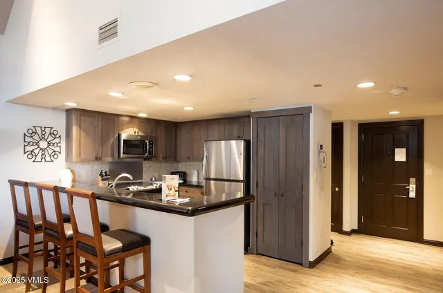 a kitchen with kitchen island granite countertop wooden cabinets and refrigerator