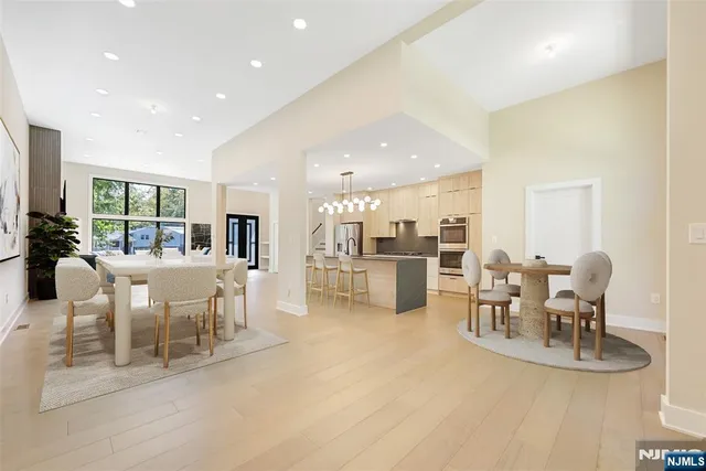 a view of an empty room and kitchen view with wooden floor