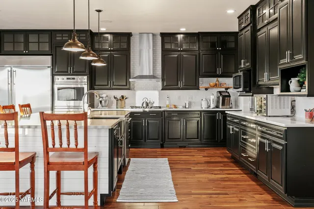 a kitchen with stainless steel appliances granite countertop a sink a stove and a refrigerator