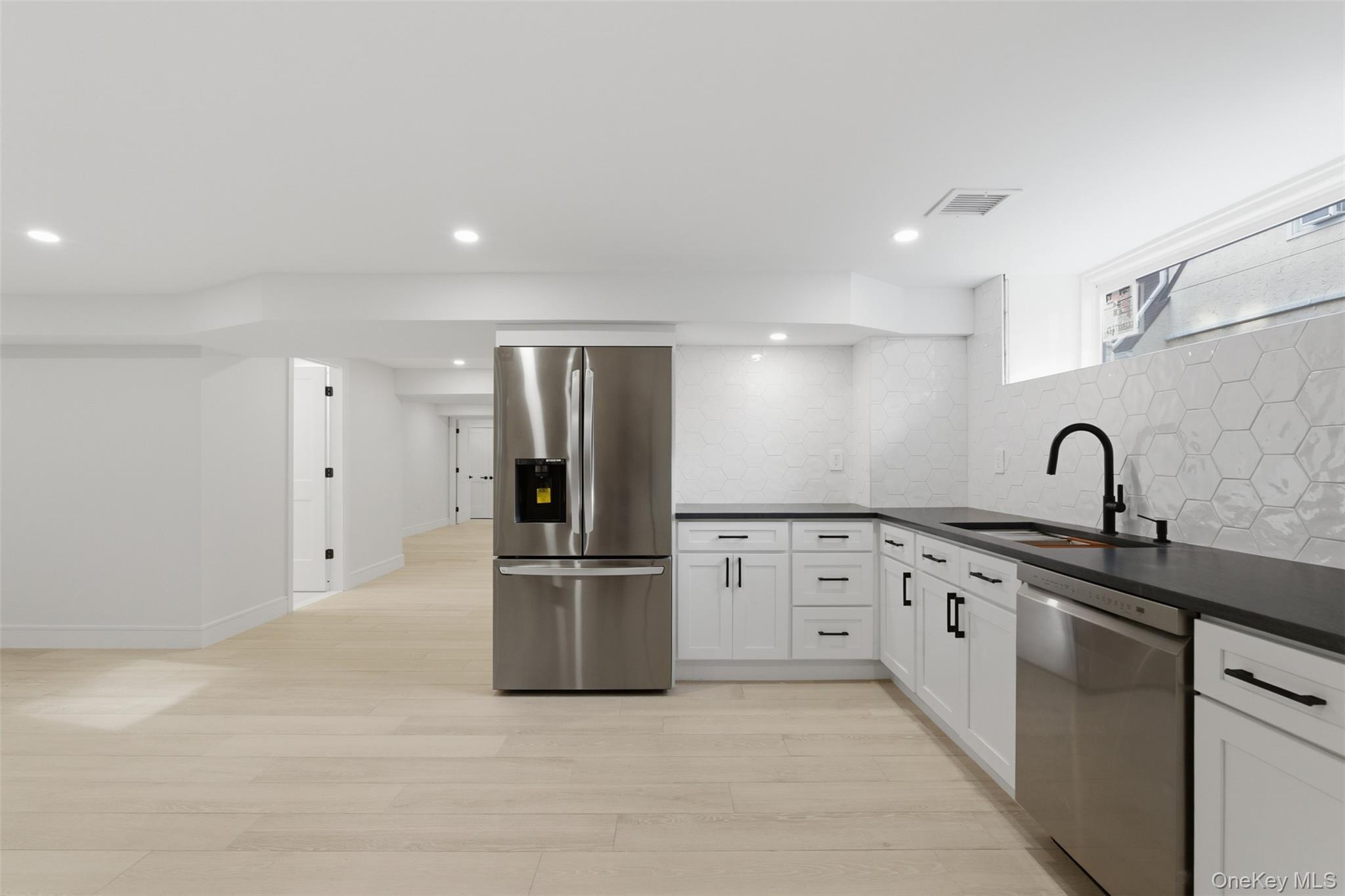 40 Calhoun Avenue New Rochelle, NY 10801 - Photo 31 of 49 L-shaped kitchen featuring white cabinetry with matte black hardware, dark countertops, a stainless steel refrigerator, and a stainless steel dishwasher