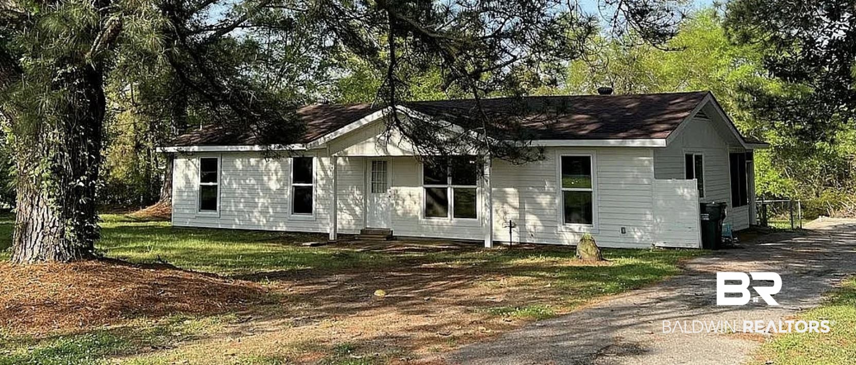 Ranch-style house featuring a front yard and view of wooded area