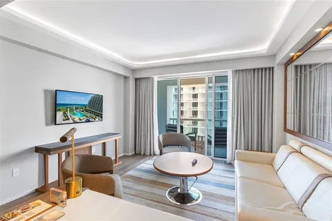 a living room with furniture a wooden floor and a potted plant