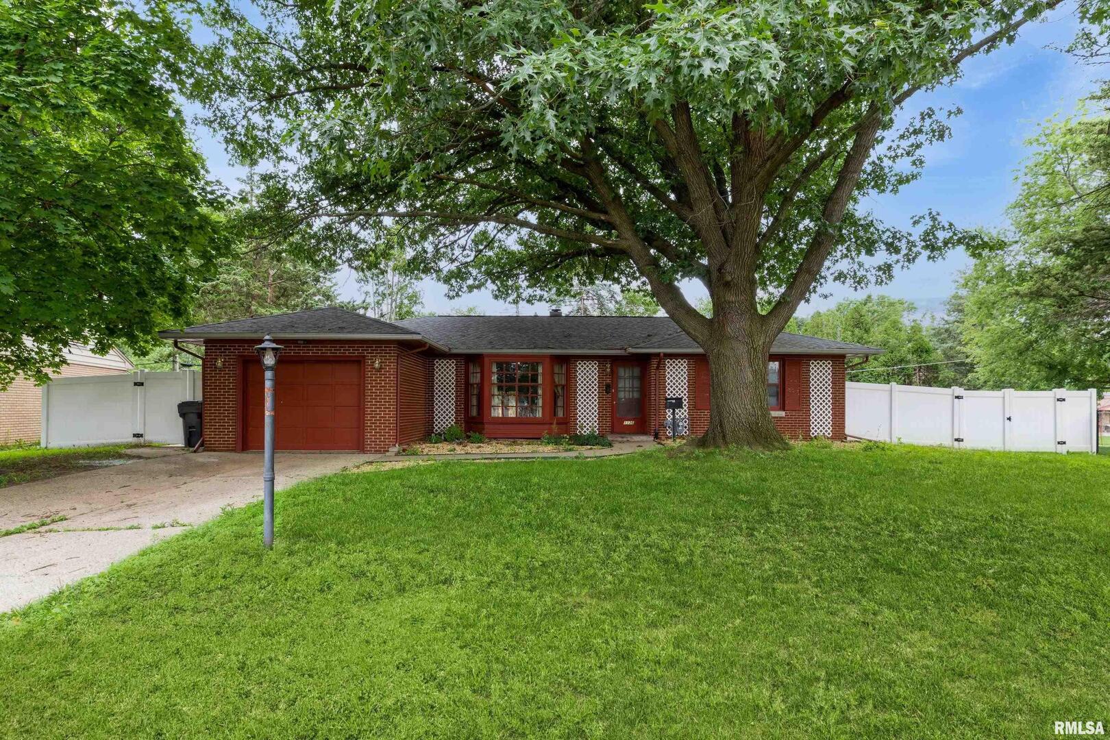 a backyard of a house with wooden fence and large tree