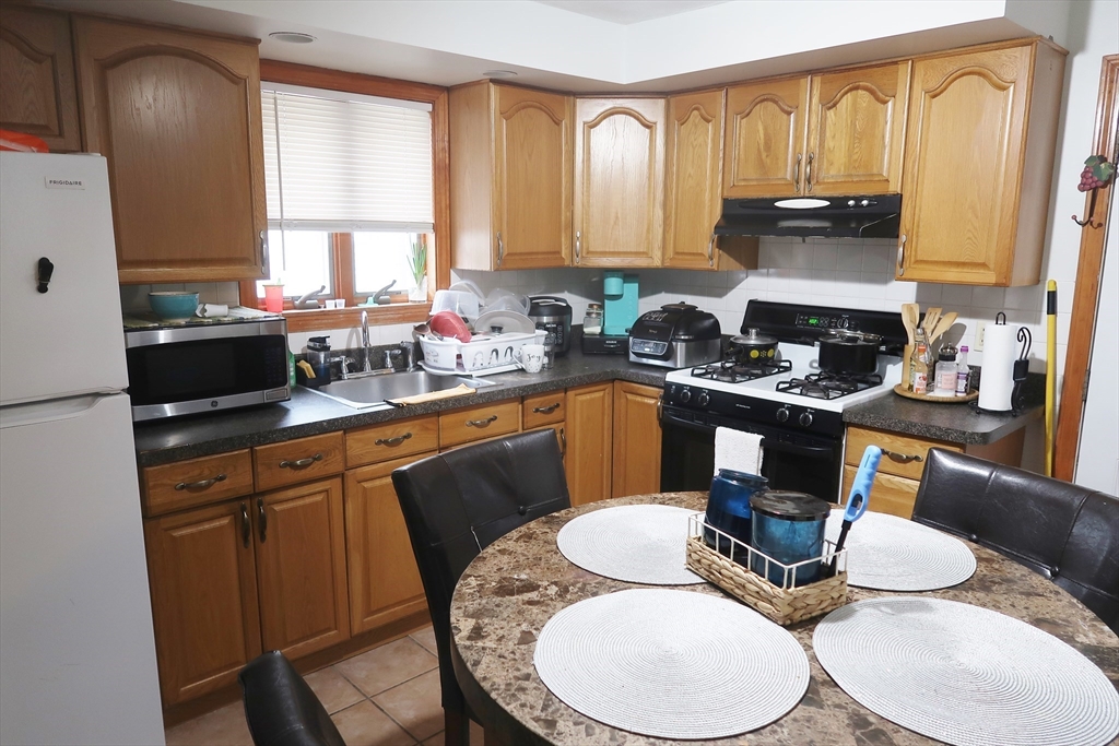 52 Taylor Street Gloucester, MA 01930 - Photo 12 of 12 a kitchen with a sink a stove and chairs