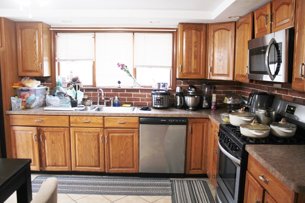 52 Taylor Street Gloucester, MA 01930 - Photo 6 of 12 a kitchen with stainless steel appliances granite countertop a stove a sink and a microwave