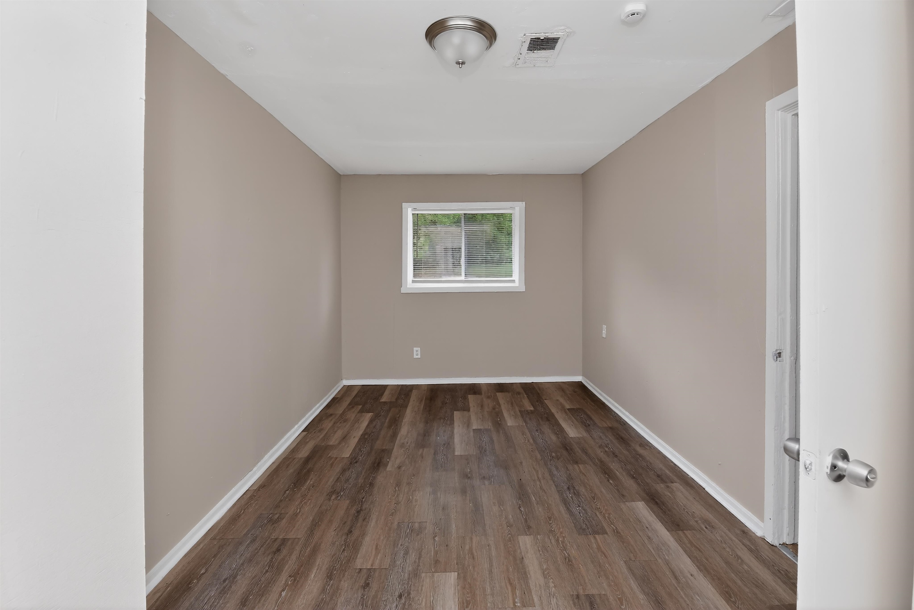 4838 Manson Road Memphis, TN 38109 - Photo 11 of 28 Neutral-toned room featuring wood-finish flooring, white baseboards, and a single window with white trim