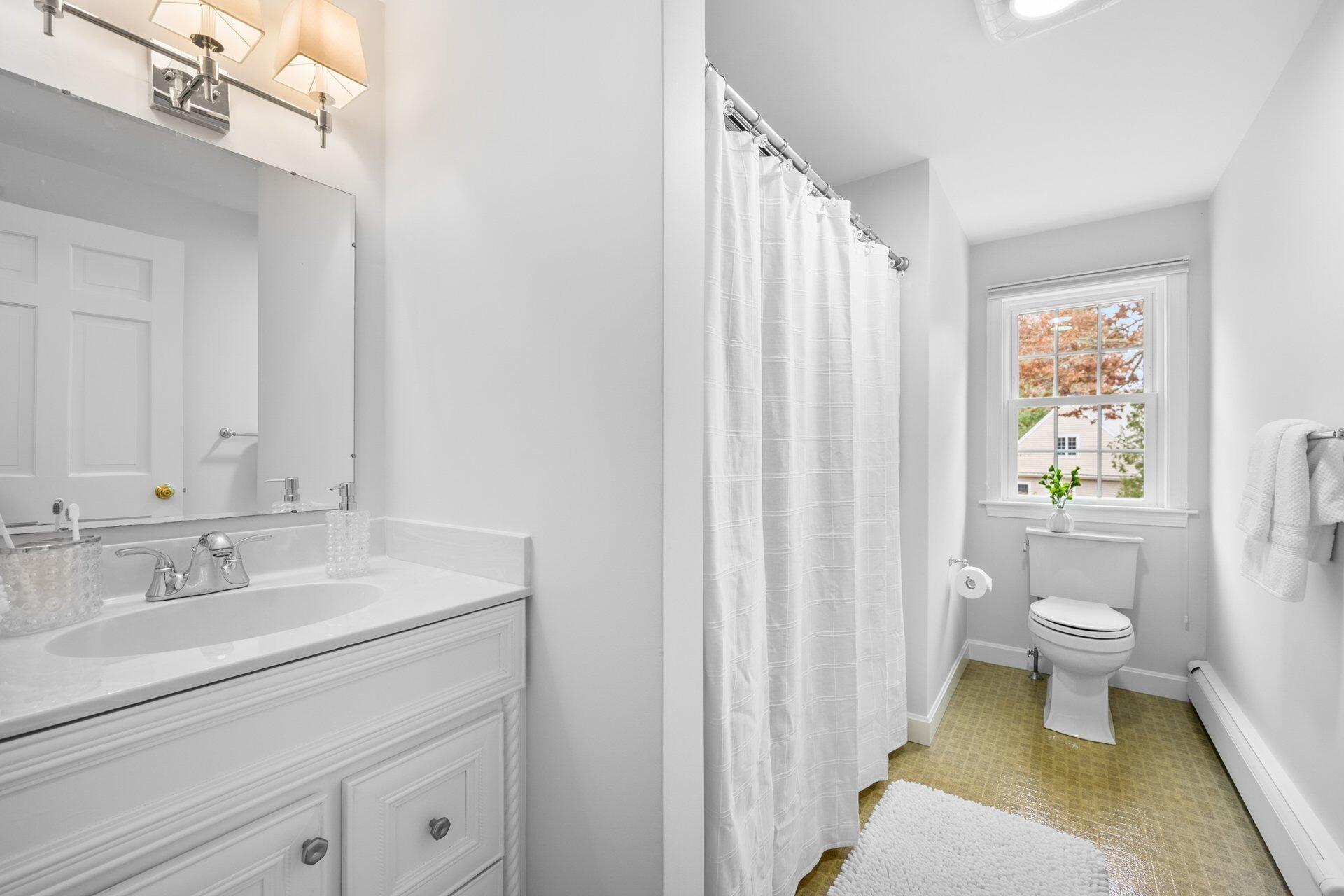 239 Clamshell Cove Road Cotuit, MA 02635 - Photo 21 of 30 a bathroom with a sink a toilet and shower curtain