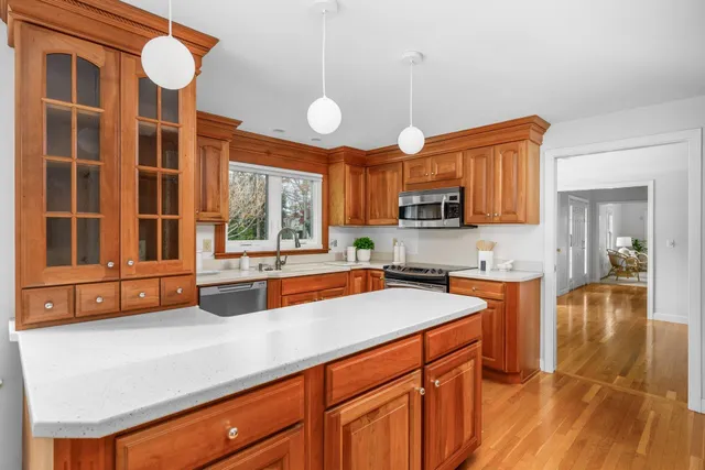 a kitchen with stainless steel appliances granite countertop a stove a sink and a refrigerator with wooden floors