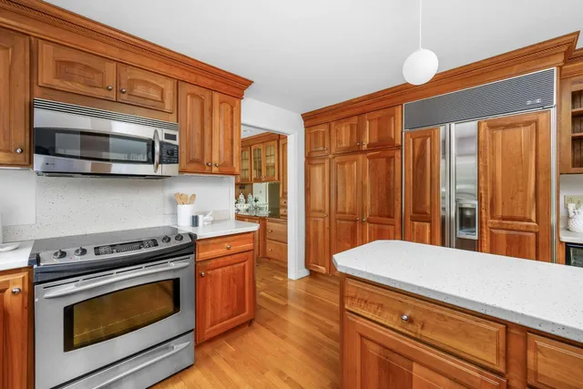 a kitchen view with wooden floor and stainless steel appliances