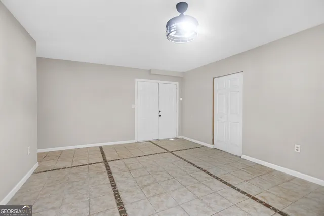 an empty room with a chandelier fan and windows