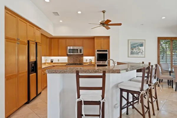 a kitchen with stainless steel appliances granite countertop a stove a refrigerator a kitchen island a dining table and chairs