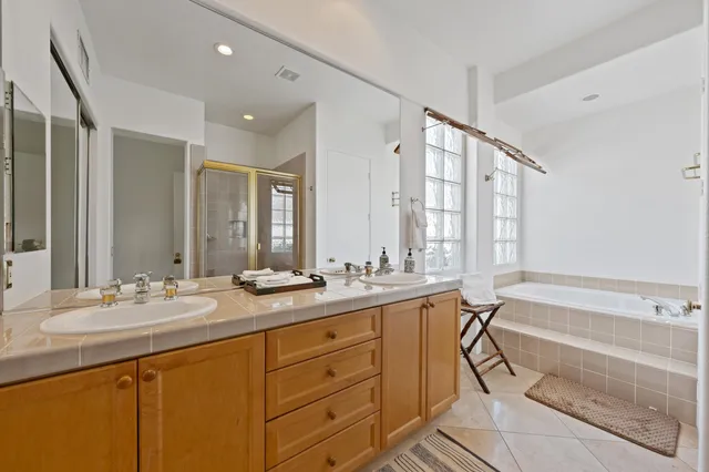 a bathroom with a double vanity sink large mirror and a bathtub