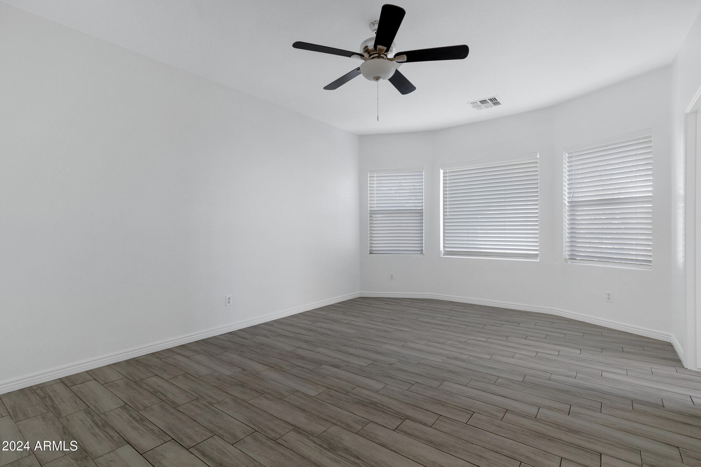 9310 West Berkeley Road Phoenix, AZ 85037 - Photo 21 of 31 an empty room with wooden floor ceiling fan and windows