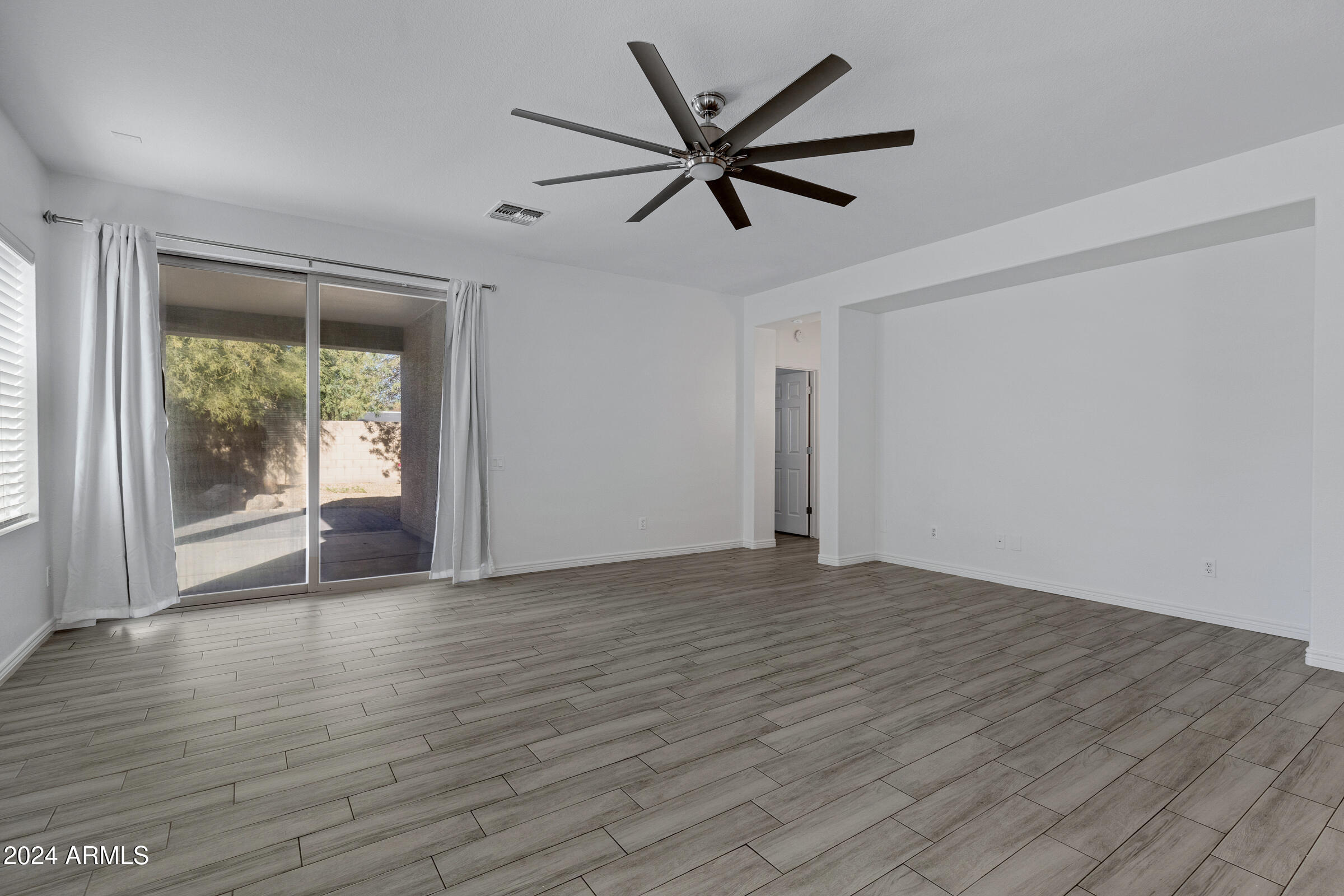 9310 West Berkeley Road Phoenix, AZ 85037 - Photo 7 of 31 a view of empty room with wooden floor and fan