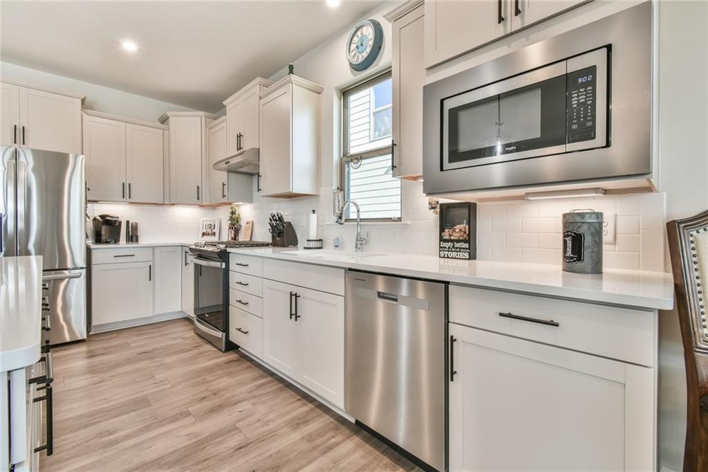 5051 Adler Court Hoschton, GA 30548 - Photo 11 of 41 a kitchen with cabinets stainless steel appliances a sink and wooden floor