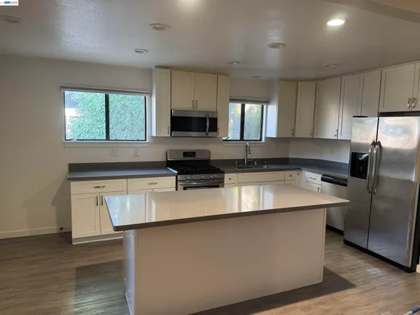 a kitchen with stainless steel appliances granite countertop a sink a stove a microwave a refrigerator and cabinets