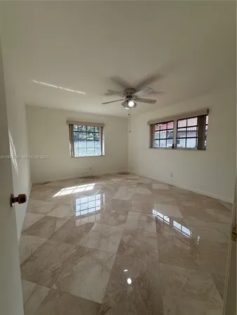 a view of a big room with windows and chandelier fan