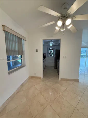 a view of an empty room with window and chandelier fan