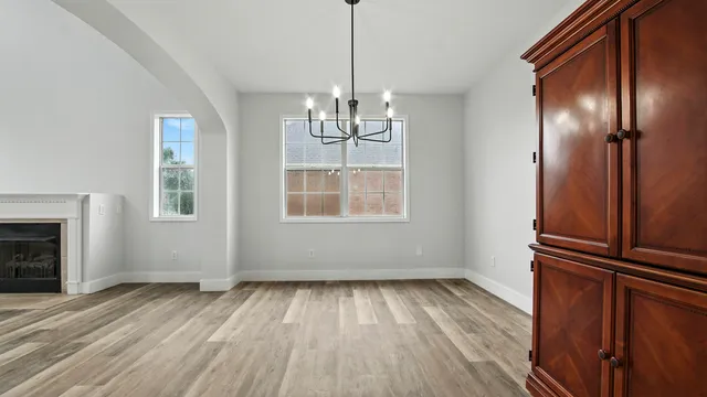 a view of an empty room with wooden floor fridge and a window