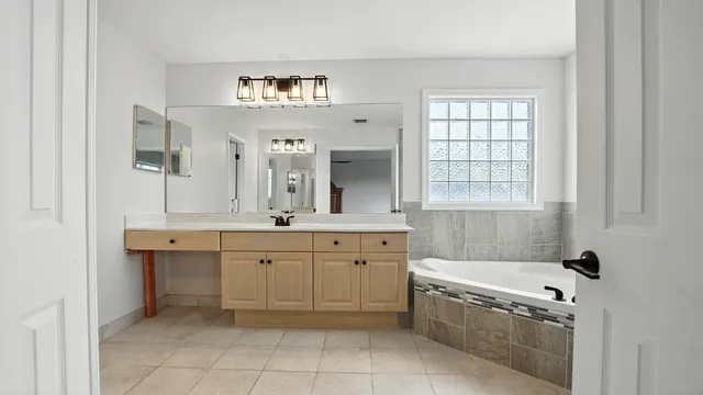 a spacious bathroom with a granite countertop sink mirror and bathtub